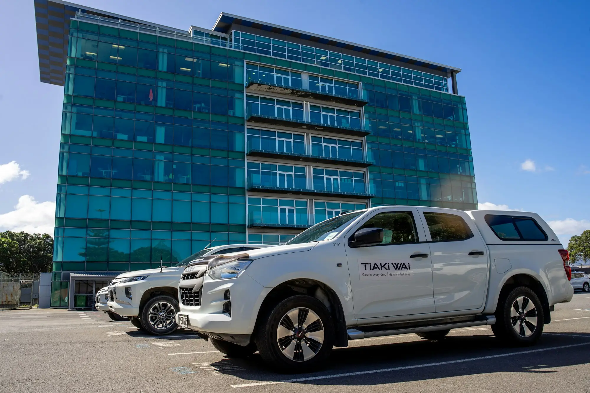 Two white right-hand-drive utes parked outside an office building