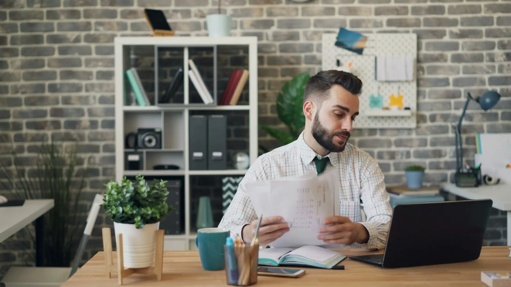 Business owner at an office desk going through loan paperwork beside a laptop