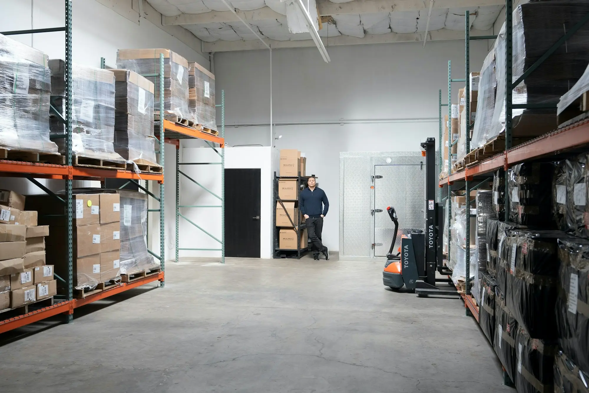 Business owner standing in a warehouse beside a forklift